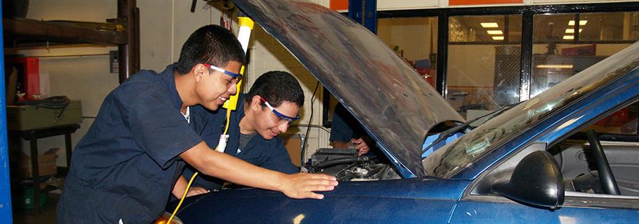 Two students look uner the hood of a car